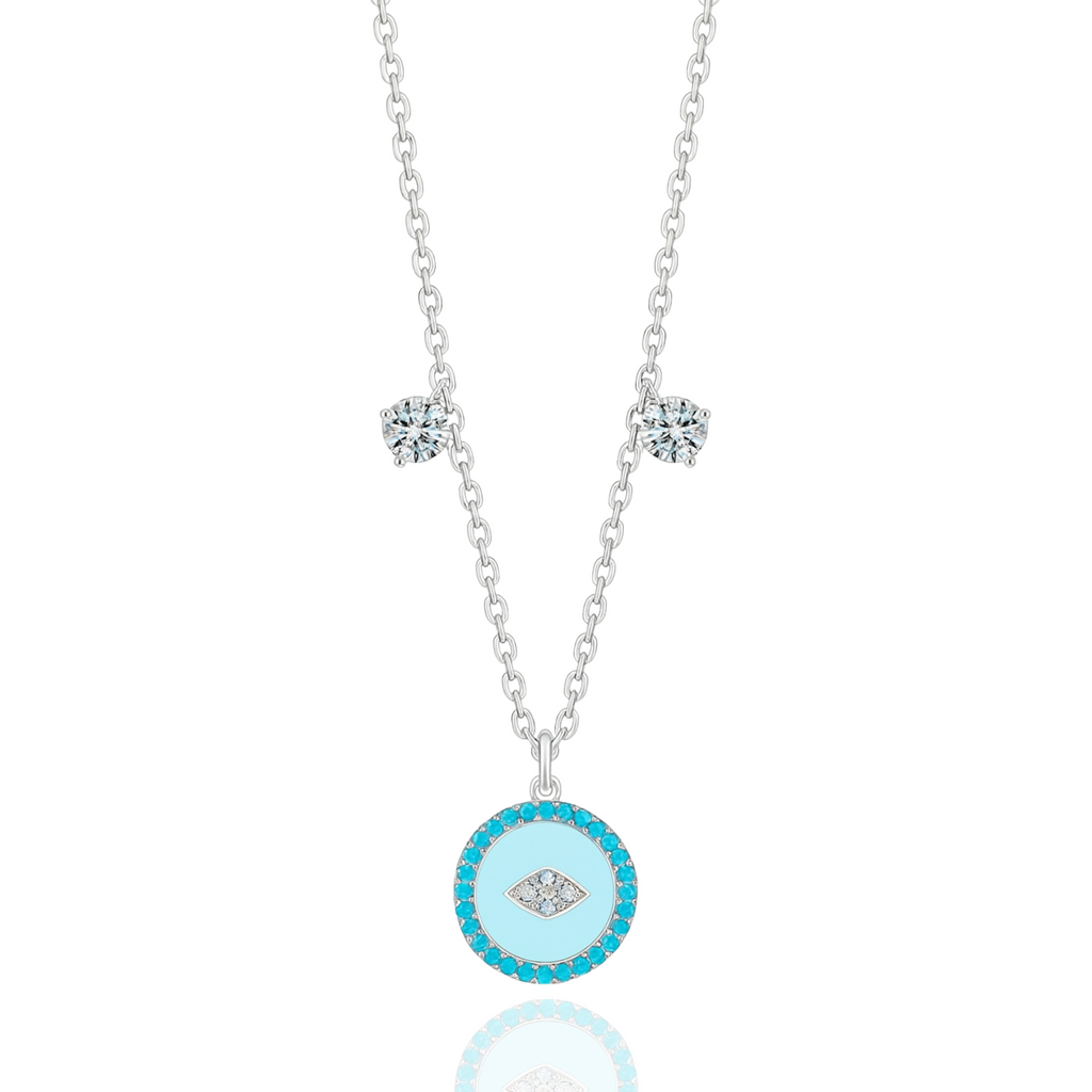 The Evil Eye Pendant Necklace by Vellura Jewellery features a sterling silver chain with two clear gemstones and a round turquoise pendant with a diamond-shaped design, combining spiritual symbolism and vibrant elegance.